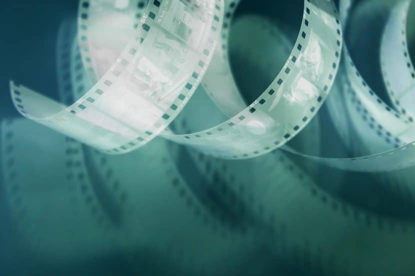 Abstracted image of a coiling length of film against a blue background, the film shining as if lit from within.
